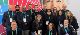 FamilyTreeDNA team members standing together at RootsTech 2025 wearing conference badges inside the Expo Hall.