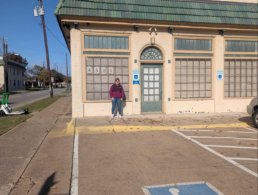 Katy Rowe-Schurwanz standing outside her ancestor’s former flower shop building in Dallas, still standing today.