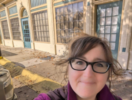 Katy Rowe-Schurwanz taking a selfie outside her ancestor’s former flower shop building in Dallas.