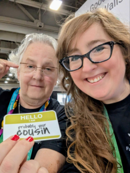 Katy Rowe-Schurwanz and Mags Gaulden holding a “probably your cousin” badge at a genealogy conference.
